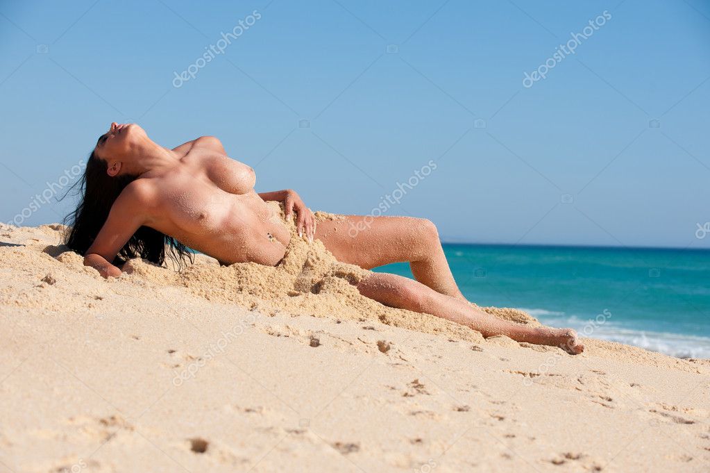 Голая няшка лежит на пляже во время прибоя